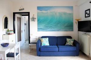 un sofá azul en una sala de estar con una pintura en la pared en Casa Serendipity Sabaudia, en Sabaudia