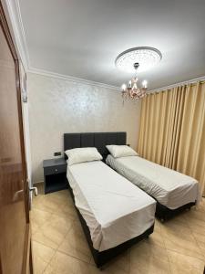 sypialnia z 2 łóżkami i żyrandolem w obiekcie Appart Hotel Excellent w mieście Nador