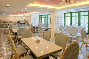 a dining room with tables and chairs and windows at Siri Heritage Bangkok Hotel - SHA Extra Plus in Bangkok