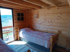 a bedroom with a bed in a log cabin at Avlija Biberović in Sjenica