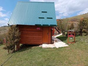 ein kleines Haus mit einem grünen Dach und einem Picknicktisch in der Unterkunft Avlija Biberović in Sjenica