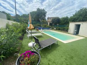 uma piscina com cadeiras e um guarda-sol e uma mesa e sidx em Gite climatisé avec piscine sur les hauteurs de Bollene em Bollène