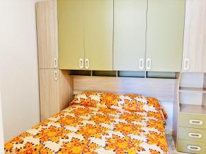 - un lit avec une couette orange et blanche dans l'établissement Condominio GIULIANA, à Bibione