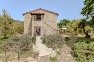 una vista esterna di una casa in pietra con giardino di Agriturismo Il Mulino delle canutole a Magione