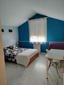 sypialnia z łóżkiem i niebieską ścianą w obiekcie Le champ Vert 