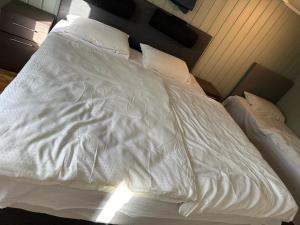 uma cama não feita com lençóis e almofadas brancas em Leilighet i kjelleren nær Sandefjord Torp em Sandefjord