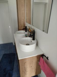 La salle de bains est pourvue d'un lavabo blanc et d'un miroir. dans l'établissement Chambre avec vue sur jardin et salle de bain à partager, à Cluses