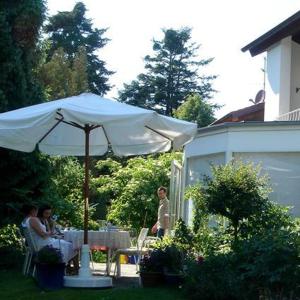 two people sitting at a table under an umbrella at Hotel Ebnet Garni in Lindau