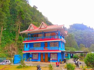una gran casa azul con techo rojo en Sikkim Silk Route Riverside Resort, Rongli, en Rongli