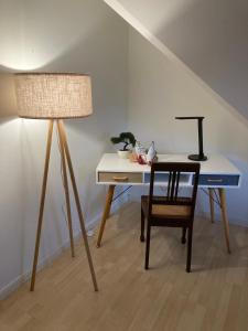 a desk with a chair and a lamp next to a table at Gästewohnung 25 in Wildeshausen