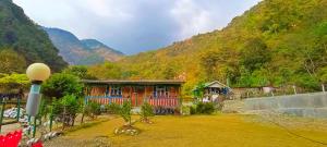 una pequeña casa en una colina con una montaña en Sikkim Silk Route Riverside Resort, Rongli, en Rongli