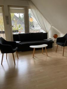 a living room with a black couch and a table at Gästewohnung 25 in Wildeshausen