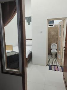 une petite salle de bains avec toilettes et une chambre dans l'établissement Harmony Resto&Homestay, à Lambangkuning