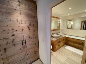 ein Badezimmer mit zwei Waschbecken und einer Holzwand in der Unterkunft Elegant apartment in Flims close to Lake Caumasee in Flims