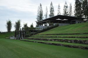 a building on top of a hill with a grass field at The Farmhouse at Polo Escape in Ban Pong