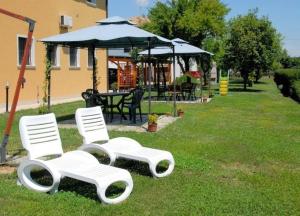 two white chairs and an umbrella in the grass at Schöne Wohnung in Venedig mit Garten und Grill - b57251 in Tessera