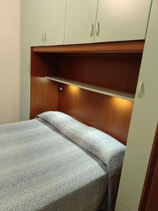 Schlafzimmer mit einem Bett mit einem Kopfteil aus Holz und Schränken in der Unterkunft Condominio Carina in Bibione