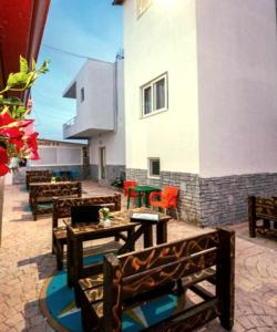 a patio with wooden benches and tables and a building at Residence Vera in Ksamil