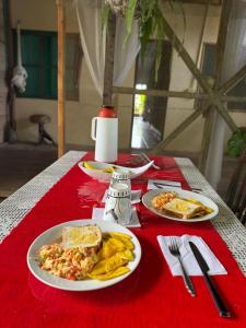 einem Tisch mit zwei Teller Essen auf einem roten Tischtuch in der Unterkunft Refugio Maiku Puerto Nariño in Puerto Nariño