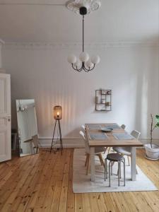 comedor con mesa, sillas y lámpara de araña en Renovated Georgian esque style apartment, en Malmö