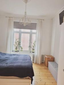 Un dormitorio con una cama azul y una lámpara de araña. en Renovated Georgian esque style apartment, en Malmö