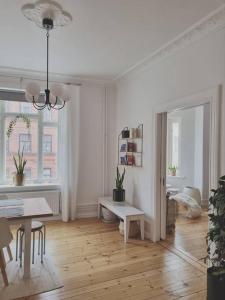 a white living room with a table and a dining room at Renovated Georgian esque style apartment in Malmö