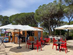 a patio with tables and red chairs and umbrellas at Appartement 4 Personnes entièrement rénové en oct 25 Domaine de Valescure in Saint-Raphaël