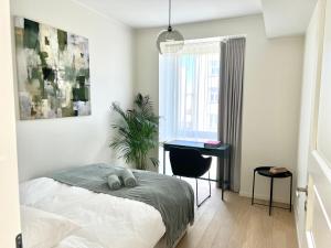 a bedroom with a bed and a desk and a window at Brand new city centre apartment, free parking spot in Tallinn