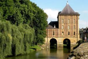 um grande edifício de tijolos com uma ponte sobre um rio em Sélénite, Chaleureuse & cocooning em Bogny Sur Meuse