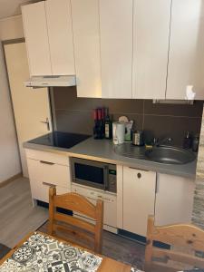 a kitchen with white cabinets and a sink at Cosy 2 pièces proche Châtel in Abondance