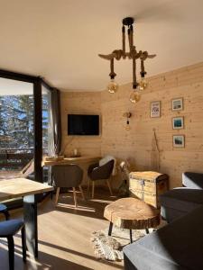a living room with tables and chairs and a television at Appartement au pied des pistes à Chantemerle in Saint-Chaffrey