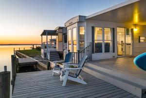 a house on a dock with two chairs on a deck at Sea La Vie Beach Cottage in Virginia Beach