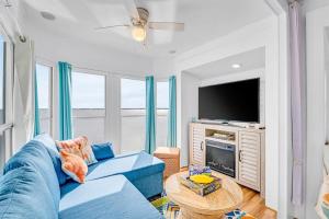 a living room with a blue couch and a tv at Sea La Vie Beach Cottage in Virginia Beach