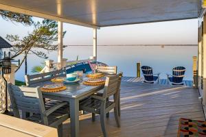 a wooden deck with a table and chairs on the water at Sea La Vie Beach Cottage in Virginia Beach