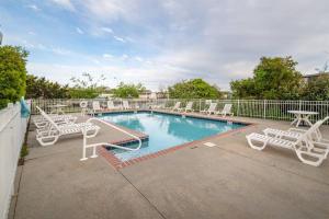 a swimming pool with white chairs and a table at Sea La Vie Beach Cottage in Virginia Beach