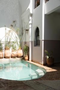a swimming pool in a building with potted plants at Riad Sashema in Marrakesh