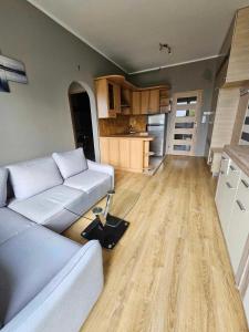 een woonkamer met een witte bank en een keuken bij Apartament kamienica in Gdynia