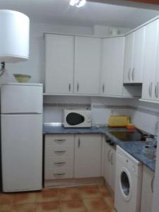 a kitchen with white cabinets and a white refrigerator at La casa de Paco y Lola in San José