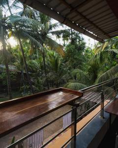 アリバグにあるSadhana Homestayの木製ベンチとヤシの木があるバルコニー