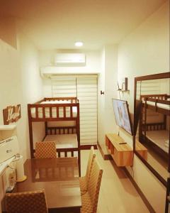 um quarto com 2 beliches, uma mesa e cadeiras em The ICONIC: Comfortable living by Awsom Phil em Manila