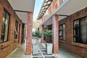 a brick hallway with two potted trees in pots at Emara 27 in Potchefstroom