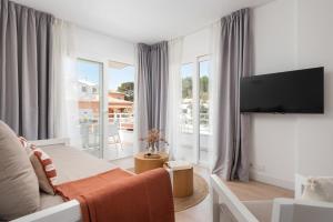a living room with a couch and a tv at Bauló Mar Apartments in Can Picafort