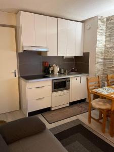 a small kitchen with white cabinets and a table at Cosy 2 pièces proche Châtel in Abondance