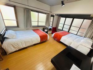 two beds in a room with two windows at Ueno Iriya hostel in Tokyo