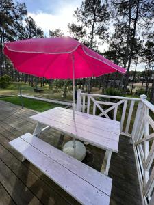 a picnic table with a pink umbrella on a deck at Villa MA&VA in Lacanau-Océan