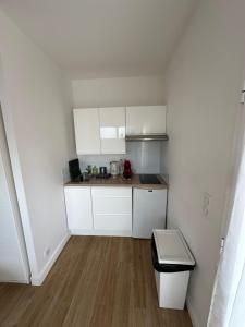 a small kitchen with white cabinets and a wooden floor at Villa MA&VA in Lacanau-Océan