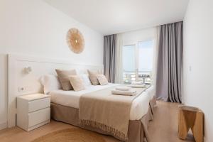 a white bedroom with a large bed with a window at Bauló Mar Apartments in Can Picafort +47 photos