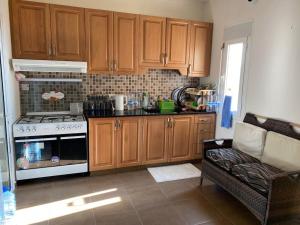 Holiday apartment in zahle with a Panoramic View في زحلة: مطبخ مع خزائن خشبية وموقد وأريكة