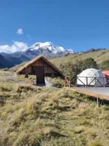 ein Zelt und ein Gebäude mit Bergen im Hintergrund in der Unterkunft Chimborazo Basecamp in Chimborazo
