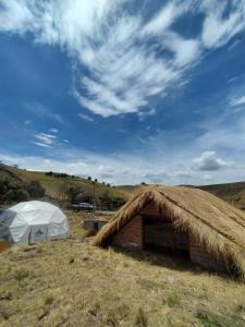 ein Zelt und ein Gebäude mit Heudach in der Unterkunft Chimborazo Basecamp in Chimborazo